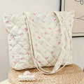 Quilted bag with pink bow pattern on a woven surface