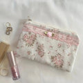 Floral pouch with makeup items on a light background